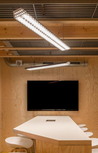 Modern conference room with White and wood unique shaped conference room with flat screen mounted on the wall and exposed wood ceiling with LED lighting 