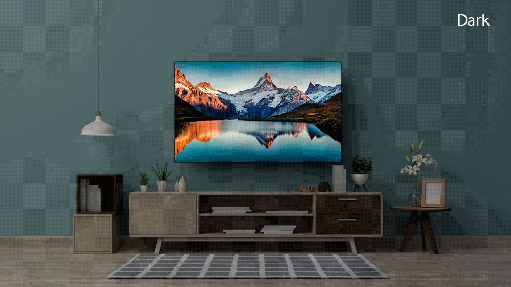 OLED TV mounted on wall showing snow capped mountain reflecting on to water. White and raw wood entertainment center below it. Small round wood side table with white flowers in a vase and picture frame. White light pendant light. 